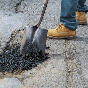 a person shoveling asphalt with a shovel